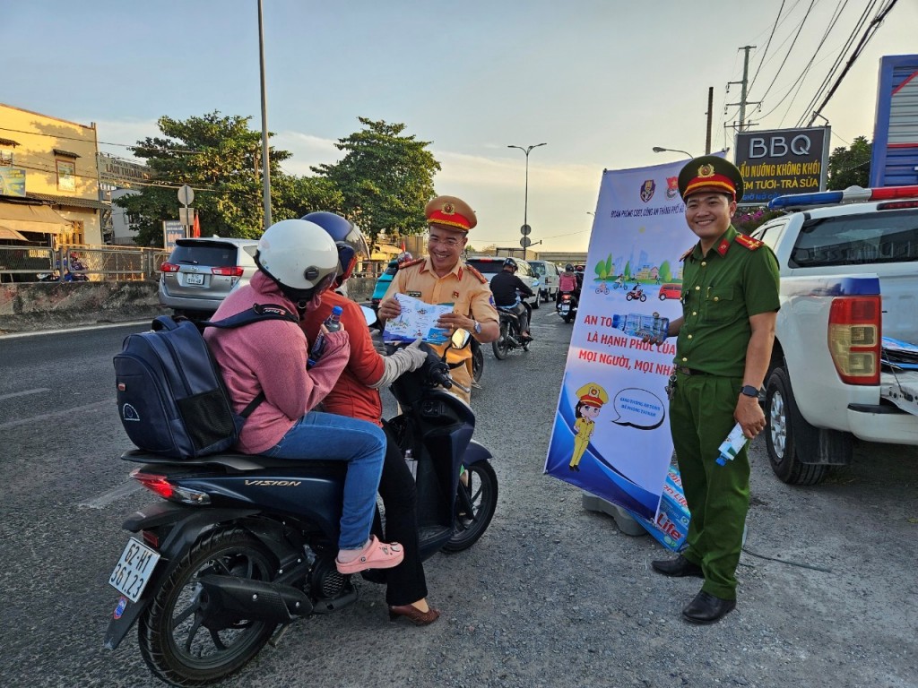 Người dân nhận nước, khăn lạnh cùng tờ rơi tuyên truyền pháp luật tại “Trạm tiếp sức” của Trạm CSGT Tân Túc