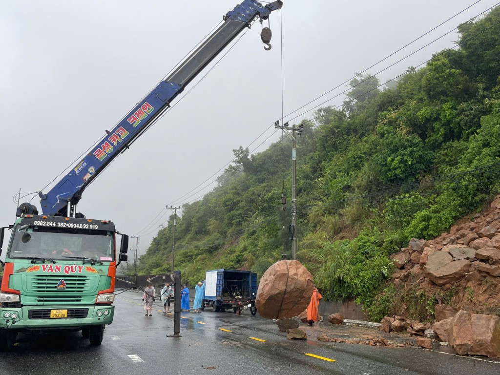 Lực lượng chức năng huy động máy móc, trang thiết bị, khẩn trương tổ chức cào, cẩu, dọn đất đá tràn xuống mặt đường (Ảnh Đ.Minh)