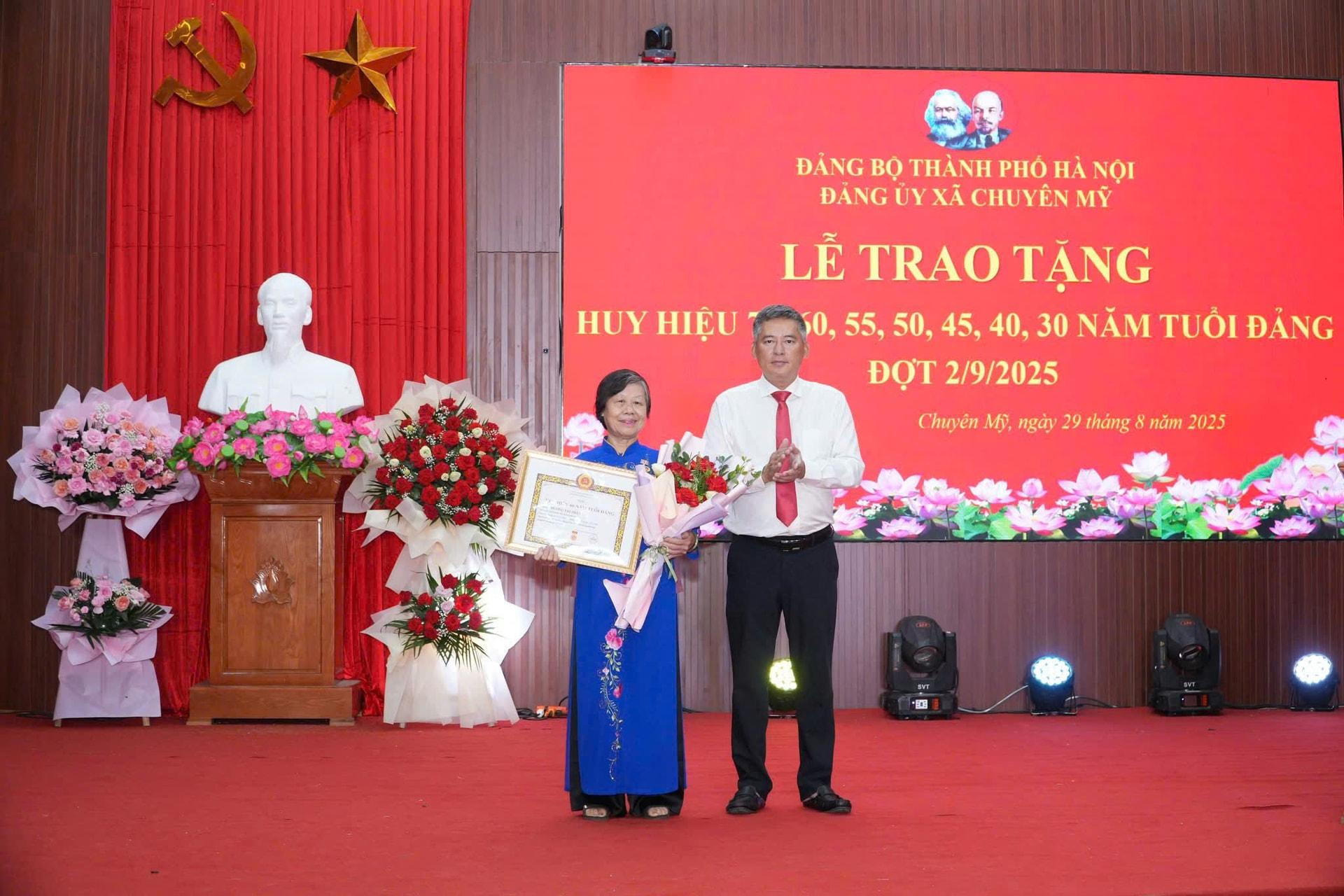 Lãnh đạo xã Chuyên Mỹ trao tặng huy hiệu đảng tặng các đảng viên. Ảnh: Đình Lộc