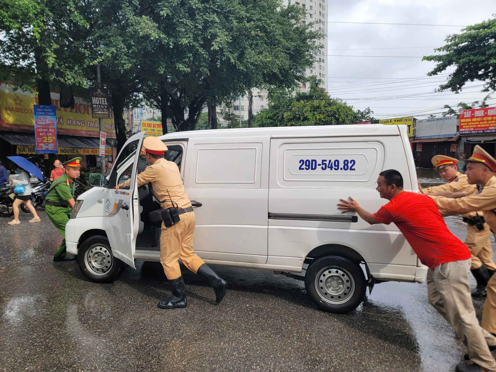 Cảnh sát giao thông, Công an phường cùng người dân di chuyển phương tiện ra khỏi khu vực ngập. Ảnh: MH